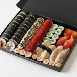 Out of the Blue Sushi - Daimyo Platter - containing 64 pieces in total of Salmon & Tuna Duo, Vegan Yum Yum, Rebel Tuna, Vegan Hug, Salmo Maki, Cucumber Maki, Sea bass Nigiri, Seasonal fish Nigiri, Salmon Sashimi, Tuna Sashimi in black serving box on white background. Allergens: Fish, Sesame, Soy, Mustard.